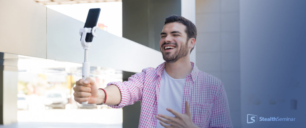 a man recording himself on a mobile device, smiling