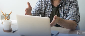 a man explaining in front of his laptop, with hand gestures