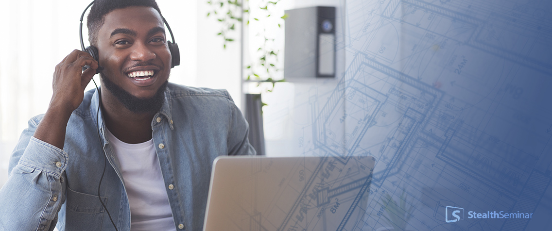 a man smiling while working on his laptop, wearing a headphone